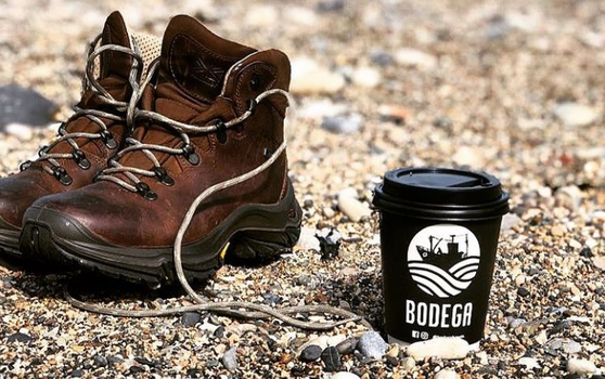 takeaway coffee cup on beach beside shoes