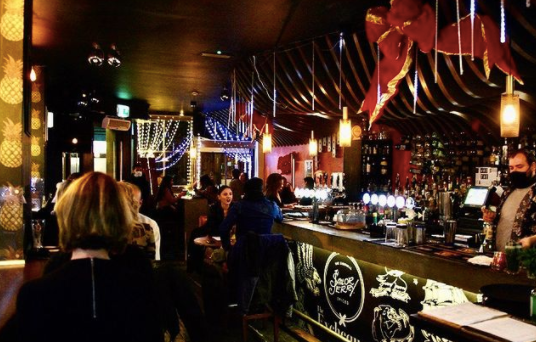 interior of the exchequer - a busy cocktail bar with christmas decorations and groups sitting at tables with drinks