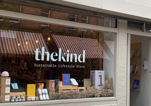 Shop Front with "The Kind - Sustainable Lifestyle Store" written on the window - books, candles and sustainable products on display