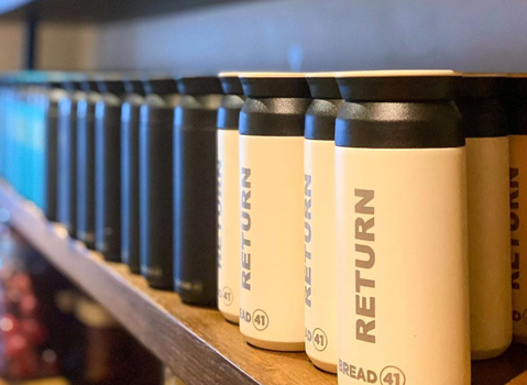 shot of bread 41's keep cups - black and white canister like cups with "return" written on the side