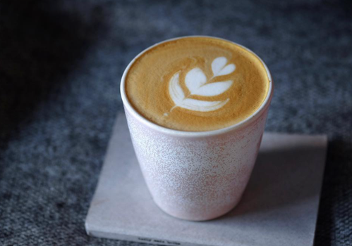Small milky coffee with latte art in a pale pink cup