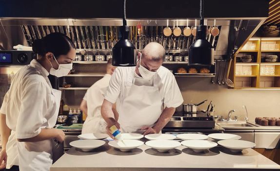 chefs in a fine dining kitchen preparing dishes