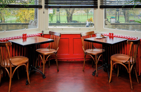 Interior of Alliance Française cafe, tables and chairs and a bay window looking out at the trinity grounds