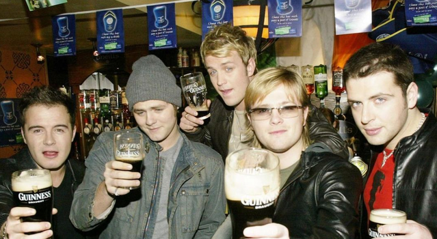 the 5 original members of Westlife in a pub all holding pints of Guinness