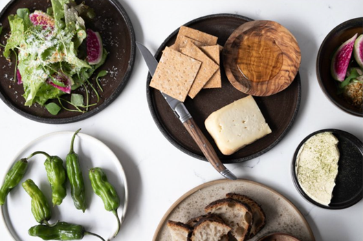 a selection of plates with cheese and crackers, salad, padron peppers and figs at Forest Ave wine bar