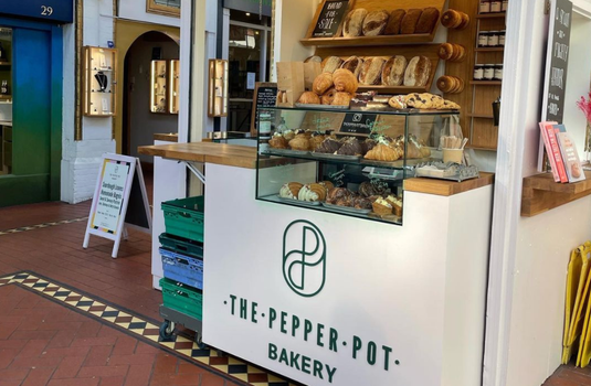 pepper pot bakery stall in georges street arcade, a cream coloured stall with green signage, shelves stacked with pastries and breads