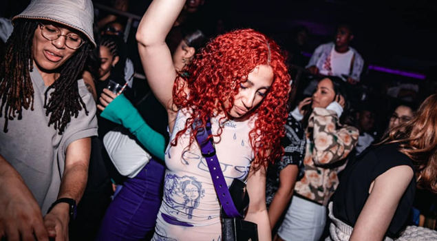 woman with red hair dancing in a nightclub, surrounded by other women