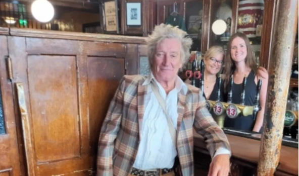 Rod Stewart posing for a photo at the bar in Gravediggers pub