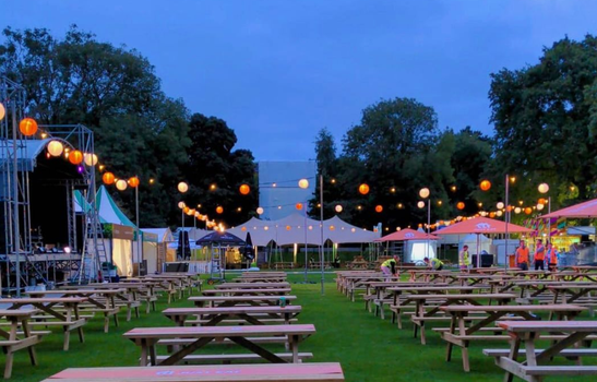 picnic tables, food stalls and fairy lights at dusk at taste of dublin
