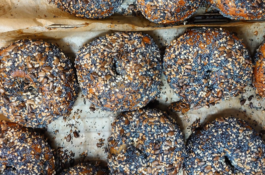 a batch of seeded bagels on a baking tray