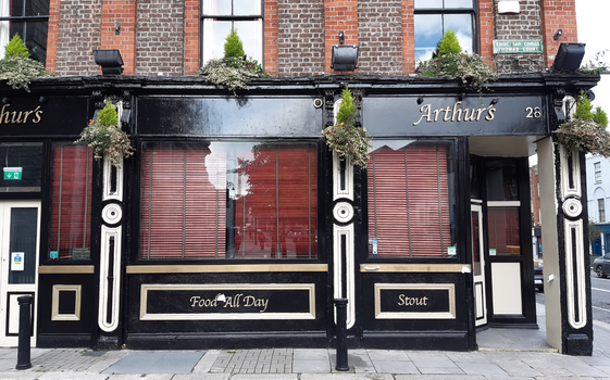 exterior shot of a black and white pub with hanging baskets and a sign that reads "Arthurs"