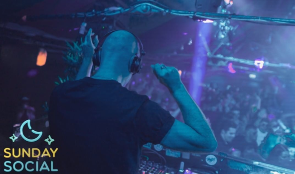person dj'ing at a busy club night, crowd can be seen dancing in the background