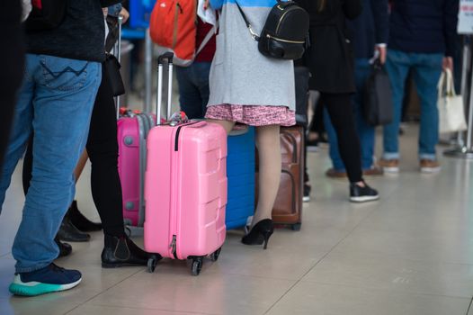 queue of people in an airport, carrying luggage