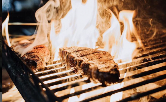 charred steak on top of a flaming grill