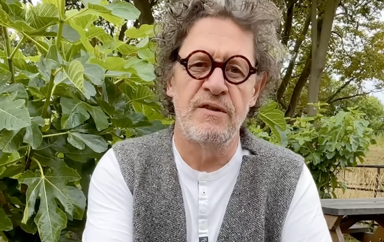 marco pierre white wearing a grey waistcoat and glasses, looking at camera