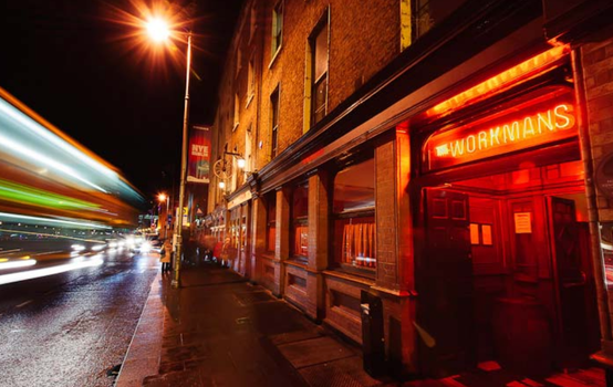 exterior of the workmans club at night, bus speeding past