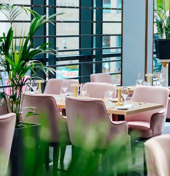 restaurant with pale pink chairs and tables, plants, dundrum town centre can be seen through window