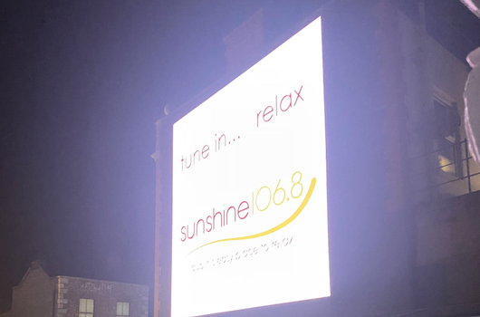 glowing billboard displaying the logo for radio station Sunshine 106.8fm