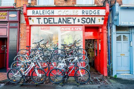 exterior of Delaneys bike shop with red shop front and several bikes parked outside