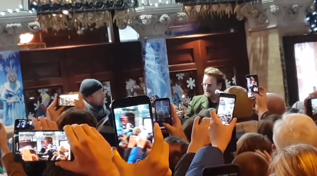 a crowd full of people with camera phones filming bono and the edge busking in dublin