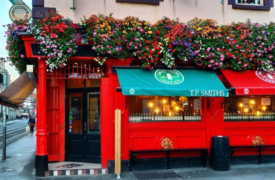 exterior of TP smiths pub in Dublin with red walls and colourful flower baskets