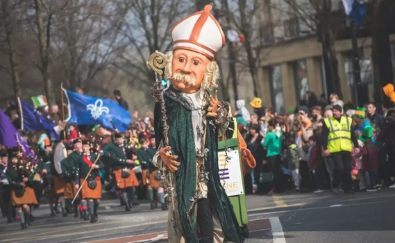 a large puppet version of St Patrick at the Paddys Day parade, with a crowd of people behind barriers