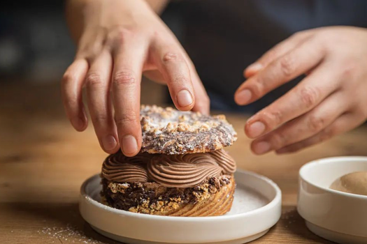 a close up of hands preparing a chocolate dessert