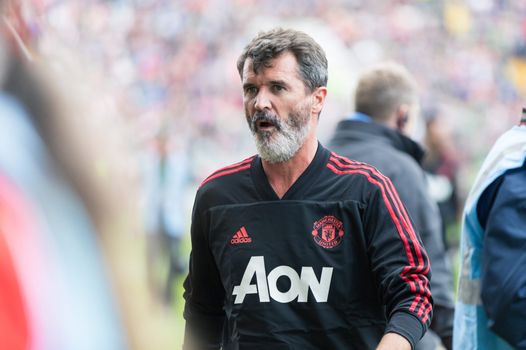 Roy Keane in a Man United training top at the sideline of a match
