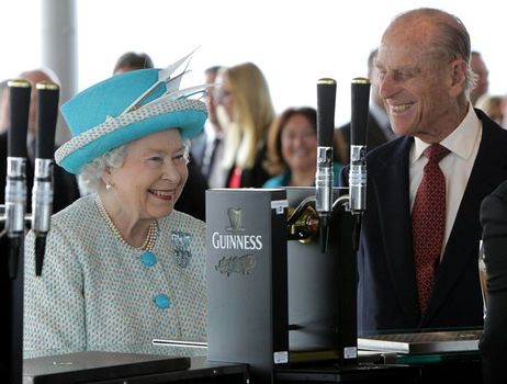 queen elizabeth and prince philip smiling in front of a guinness tap