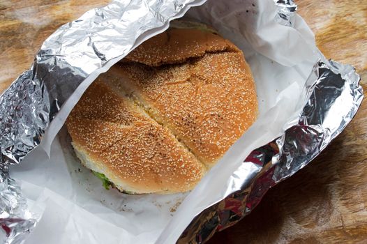 a takeaway burger wrapped in tinfoil and tissue