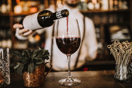 a bartender pouring a glass of red wine at a bar